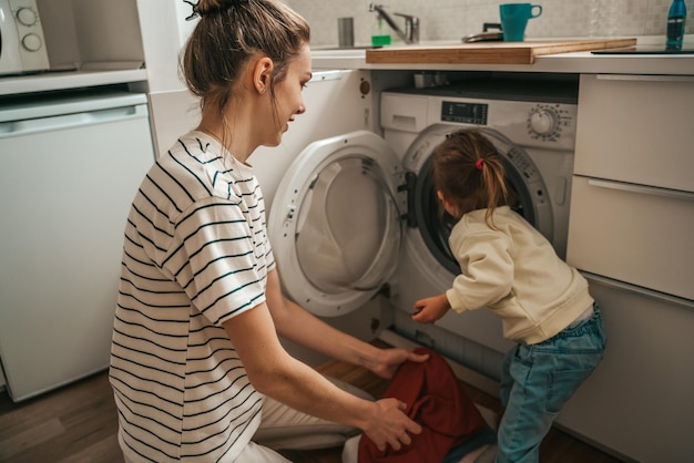 Foto mutter und tochter laden schmutzige wäsche in die waschmaschine