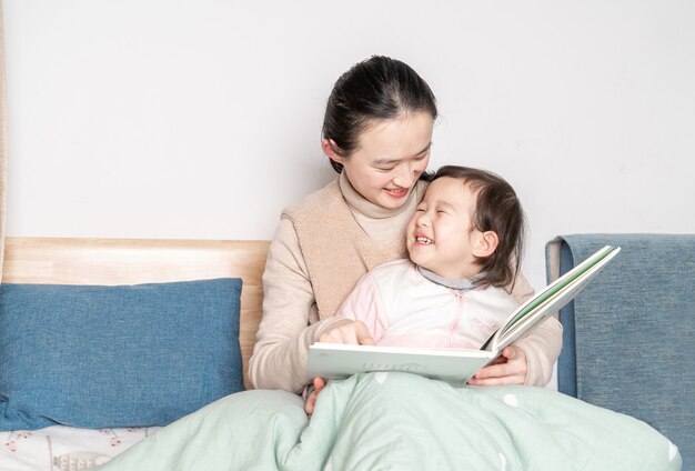 Mutter und Tochter lesen im Bett