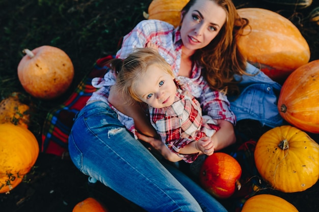 Mutter und Tochter liegen zwischen Kürbissen auf dem Feld, Halloweenabend