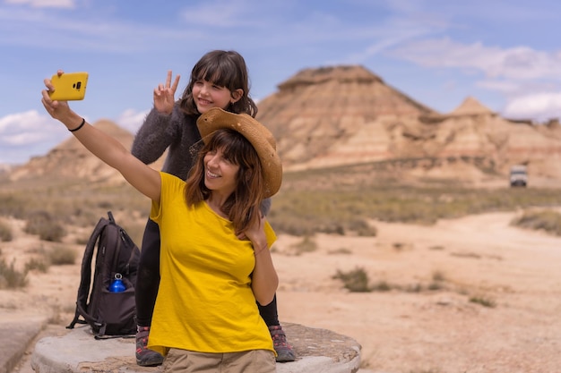 Mutter und Tochter machen ein Selfie nach einem Trekking in der Wüste