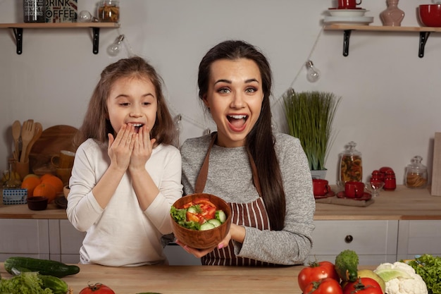 Mutter und Tochter machen einen Gemüsesalat und haben Spaß in der Küche.