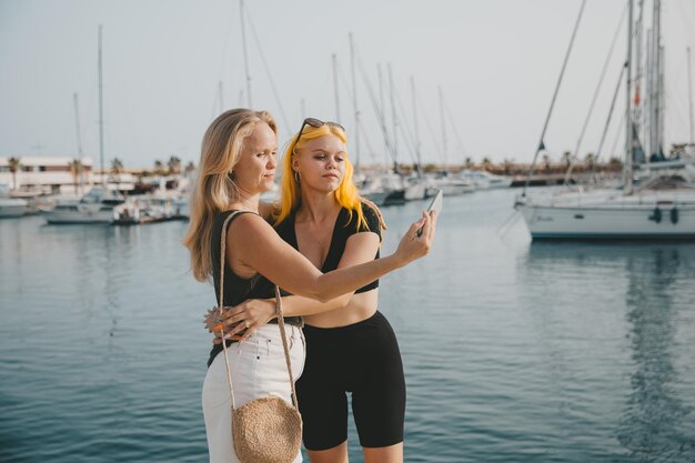 Mutter und Tochter machen Selfies vor dem Hintergrund des Meeres und der Yachten