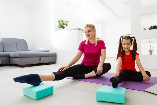 Mutter und Tochter machen zu Hause Yoga-Übungen auf der Matte.