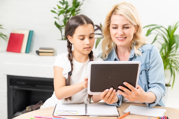 Mutter und Tochter mit digitalem Tablet zu Hause.