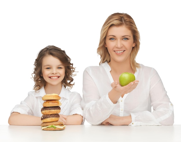 Mutter und Tochter mit gesundem und ungesundem Essen