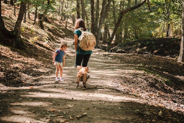 Mutter und Tochter mit Hunden beim Wandern im Wald