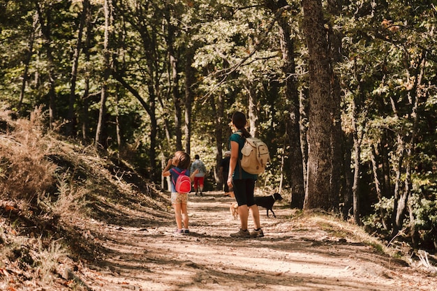 Mutter und Tochter mit Hunden beim Wandern im Wald