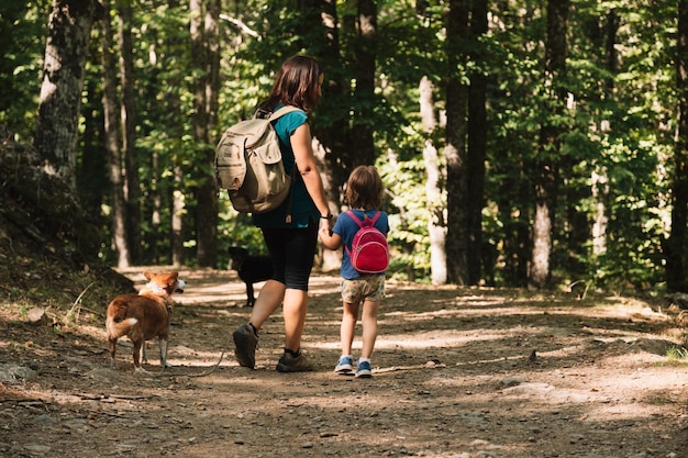 Mutter und Tochter mit Hunden beim Wandern im Wald
