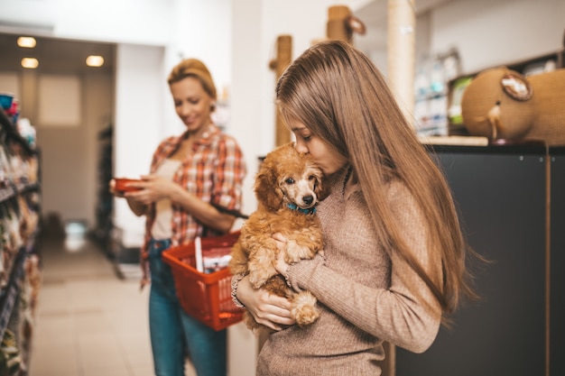 Mutter und Tochter mit ihrem Pudelwelpen in der Tierhandlung.