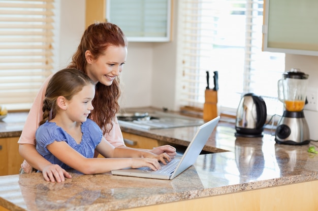 Mutter und Tochter mit Laptop in der Küche