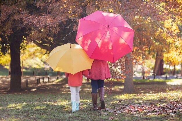 Mutter und Tochter mit Regenschirm im Park