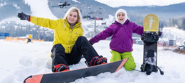 Mutter und Tochter mit Snowboards in einem Bergresort