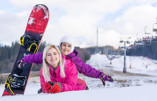 Mutter und Tochter mit Snowboards spielen im Schnee