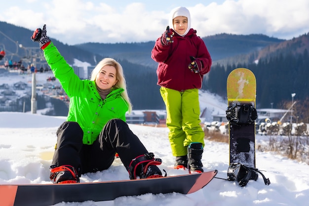 Mutter und Tochter mit Snowboards spielen im Schnee