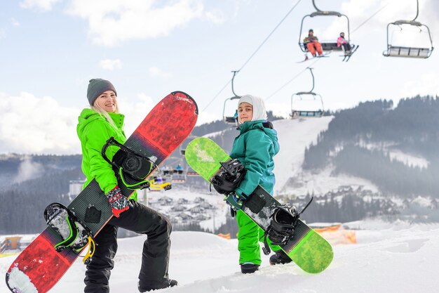 Mutter und Tochter mit Snowboards spielen im Schnee