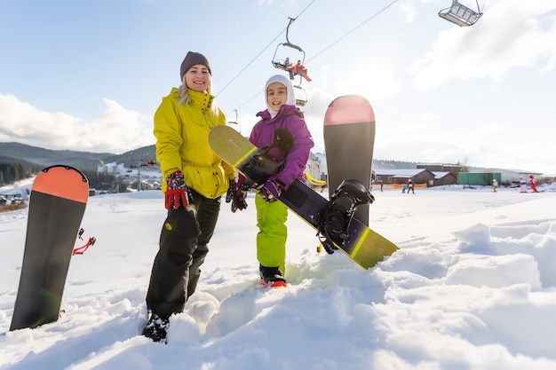 Mutter und Tochter mit Snowboards spielen im Schnee