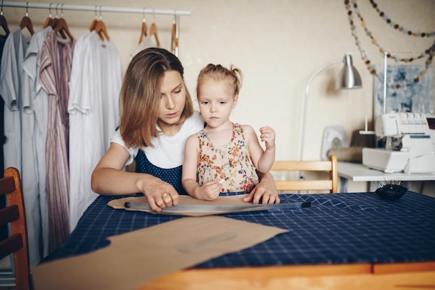 Mutter und Tochter nähen Kleider zusammen. Musterkleid.