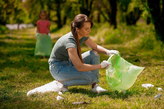 Mutter und Tochter sammeln Müll in einem Park und sehen beschäftigt aus