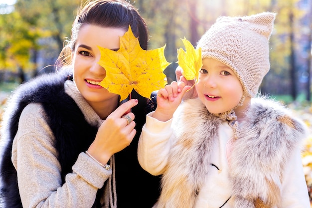 Mutter und Tochter schließen die Augen mit Herbstlaub