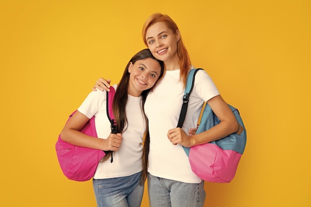 Mutter und Tochter Schulmädchen mit Schultasche bereit zu lernen Zurück zur Schule Mutter und Kind auf isoliertem gelbem Studiohintergrund Familienerziehung