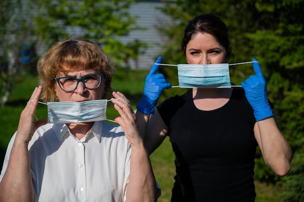 Mutter und Tochter setzen medizinische Masken auf, um die Ausbreitung der Infektion zu verhindern. Zwei ältere Frauen und Frauen mittleren Alters sind vor dem Coronavirus geschützt