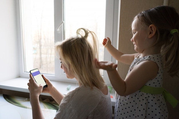 Foto mutter und tochter sitzen am fenster.