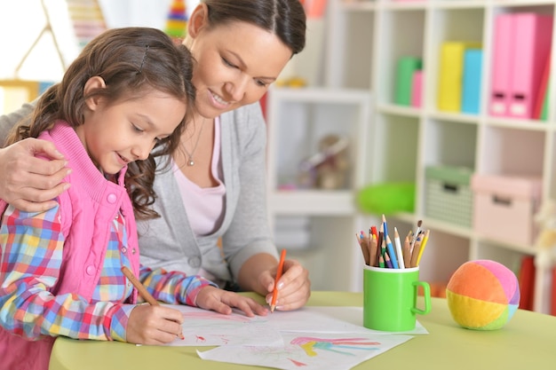 Mutter und Tochter sitzen am Tisch und zeichnen