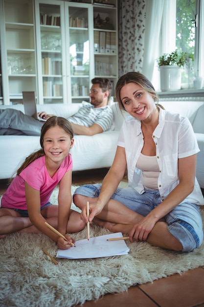 Mutter und Tochter sitzen auf dem Boden und zeichnen