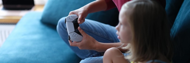 Mutter und Tochter sitzen auf der Couch und halten Computer-Joysticks Nahaufnahme