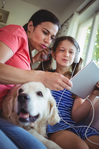 Mutter und Tochter sitzen mit Hund und verwenden digital