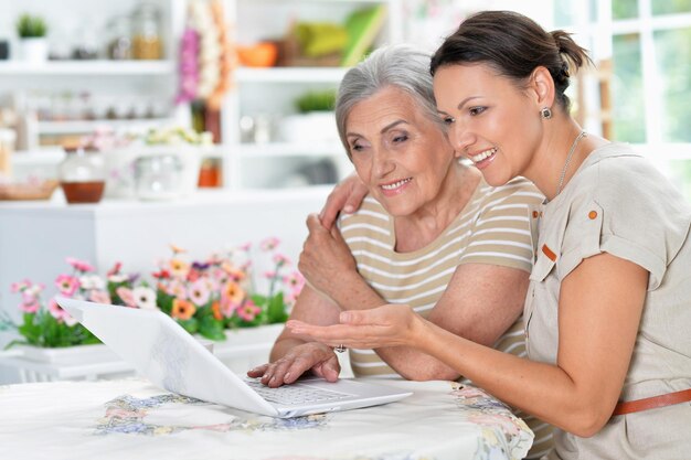 Foto mutter und tochter sitzen zu hause mit laptop am tisch