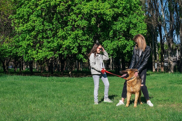 Mutter und Tochter spazieren im Park mit einer Hunderasse Deutscher Schäferhund Sommersonne