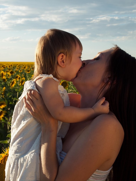 Mutter und Tochter spielen im Sonnenblumenfeld.