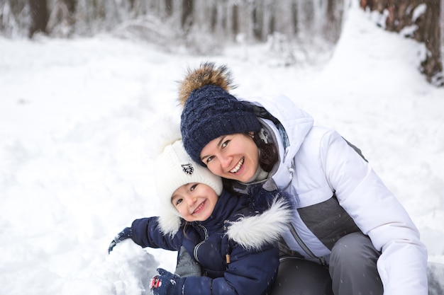 Mutter und Tochter spielen Schneespiele, bauen eine Festung, machen Schneebälle. Winterferien