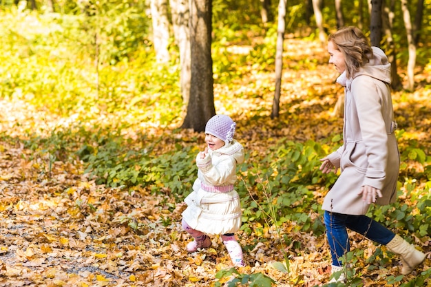 Mutter und Tochter spielen zusammen im Herbstpark.