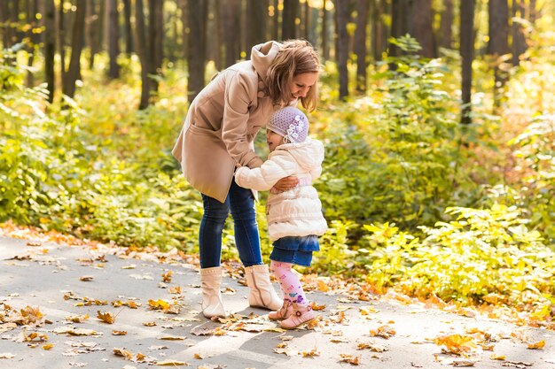 Mutter und Tochter spielen zusammen im Herbstpark.