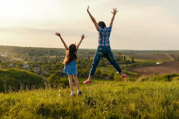 Mutter und Tochter springen bei Sonnenuntergang