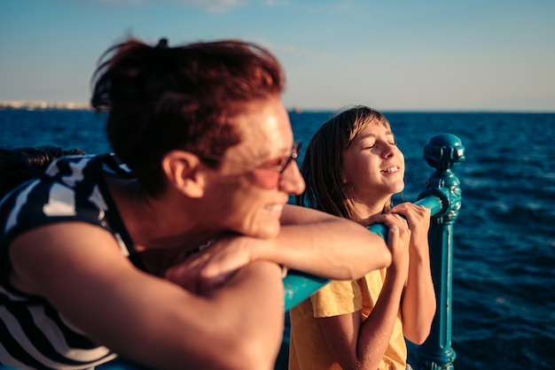 Mutter und Tochter stehen am Zaun am Meer