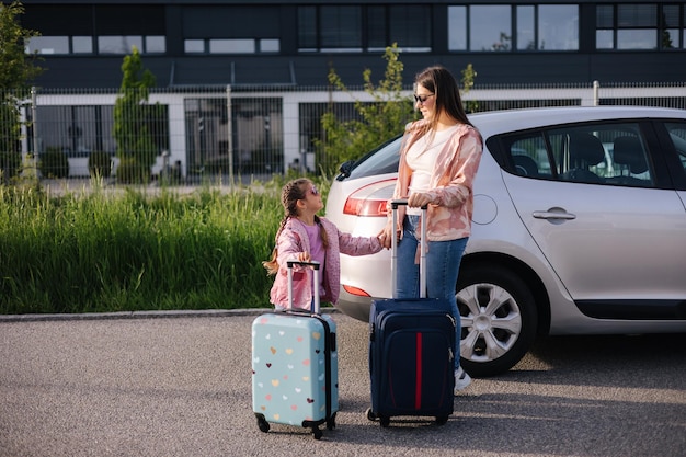 Mutter und Tochter stehen mit ihren Koffern neben dem Auto und warten auf die Reise mit der Familie