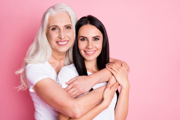 Mutter und Tochter umarmen isoliert auf rosa