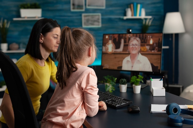 Mutter und Tochter verwenden Videoanruf-Konferenztechnologie für die moderne Kommunikation. Erwachsene und Kinder sprechen mit Oma über eine Online-Internetverbindung, während sie zu Hause sitzen