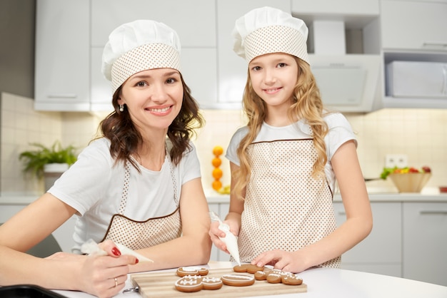 Mutter und Tochter verzieren Kekse mit Zuckerglasur.