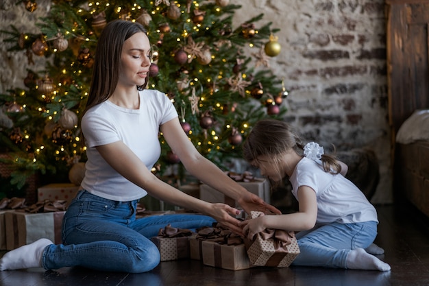 Mutter und Tochter vor dem Weihnachtsbaum, Geschenke öffnend