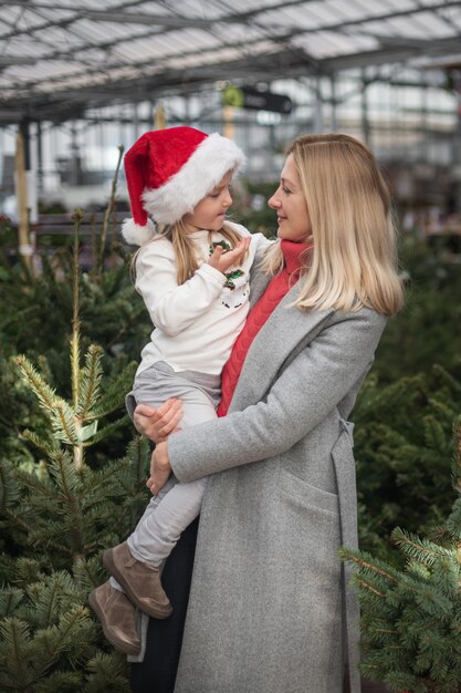 Mutter und Tochter wählen einen Weihnachtsbaum auf einem Markt.