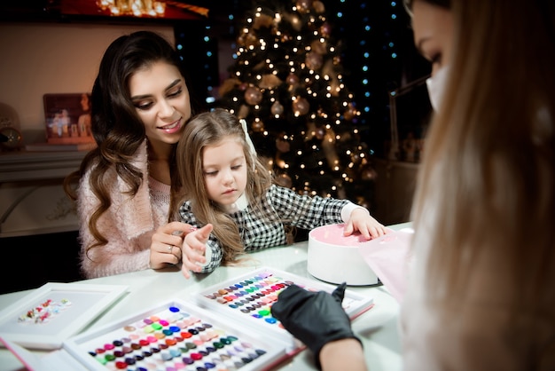 Mutter und Tochter wählen vor Weihnachten in einem Schönheitssalon die Farbe des Nagellacks.