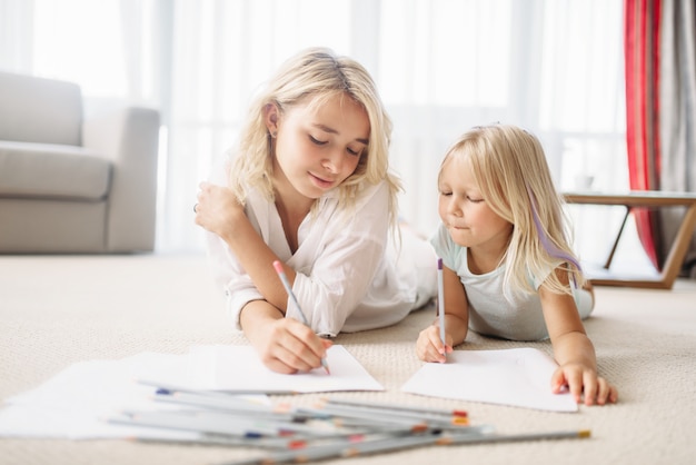 Mutter und Tochter zeichnen auf dem Boden liegend