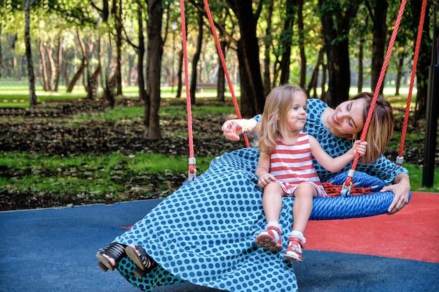 Mutter und Töchter auf einer Schaukel im Park zwischen den Bäumen Konzept Mutter Tochter Familienglück Entspannung in der Stadt