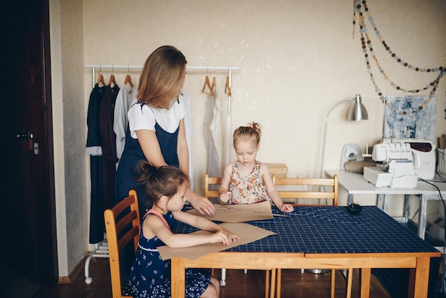 Mutter und Töchter nähen Kleider zusammen. Musterkleid.