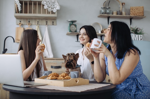 Mutter und Töchter unterhalten sich und essen Croissants in der Küche