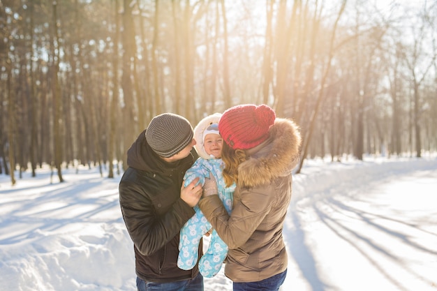 Mutter und Vater, die ihr Baby halten und im Winter draußen küssen.